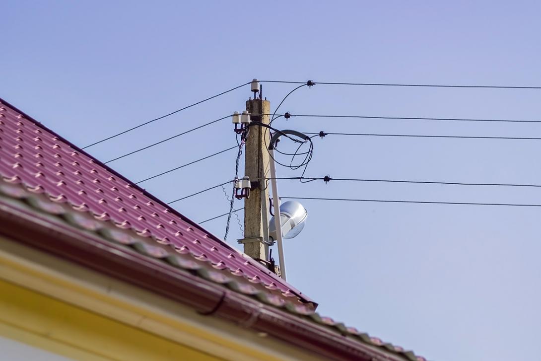 Betonový sloup s vedením nízkého napětí a trubkovým svodem ukrývajícím kabel pro napájení odběrného místa v domě v popředí (Zdroj: © IKvyatkovskaya / stock.adobe.com)