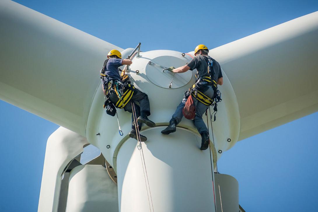 Dvojice specializovaných techniků zajišťuje revizi uchycení laminovaných listů k rotoru větrné turbíny (Zdroj: © Tarnero / stock.adobe.com)